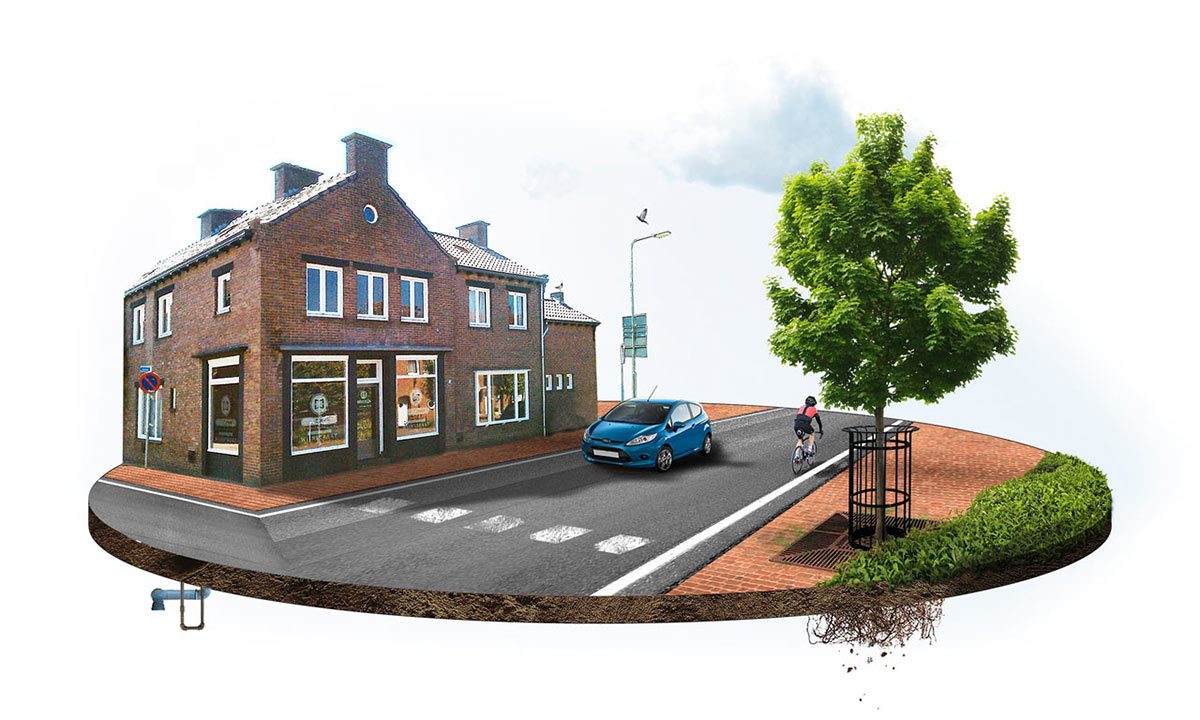 Het hoekpand in Susteren, met de etalage op de begane grond, de straat ervoor en een boom aan de overkant.
